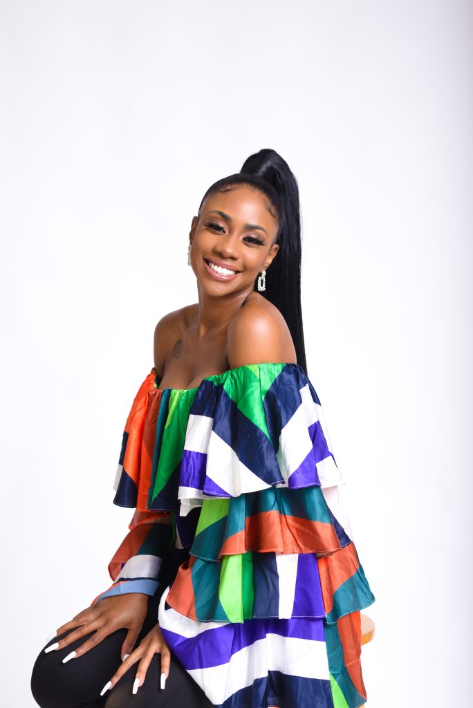 Sucoyia smiling in a colorful off-shoulder fashion top during a studio portrait session.